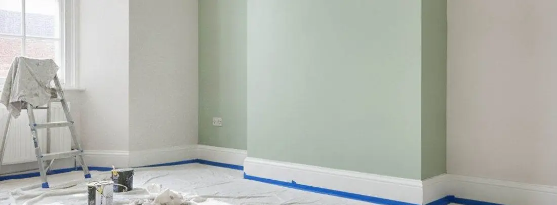 Una stanza appena tinteggiata: scala, teli sul pavimento e il battiscopa protetto dal nastro.